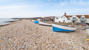 A pebble beach with houses and a boat. - Sea Esta, Selsey - sleeps 4 guests  in 1 bedroom (Selsey)