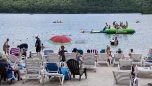 Una playa junto al lago con sillones de descanso y balsas inflables.