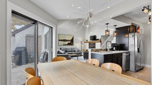 Una cocina moderna con una isla central, electrodomésticos de acero inoxidable y una zona de comedor con mesa y sillas de madera.