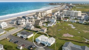 Vue aérienne d’une zone résidentielle côtière, avec des maisons, une plage et une route.