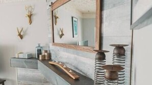 A modern kitchen with a stone countertop, a wooden-framed mirror, and decorative antlers on the wall.