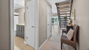 A hallway with a kitchen area, a staircase, and a seating area with a chair and a plant. - 10G, Sandy´s Beach Retreat (Destin)