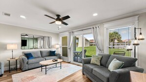 A modern living room with two grey sofas, a coffee table, and a ceiling fan.