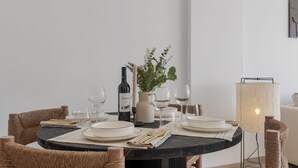 A dining table set with plates, glasses, and cutlery, a bottle, and a candle in a vase.