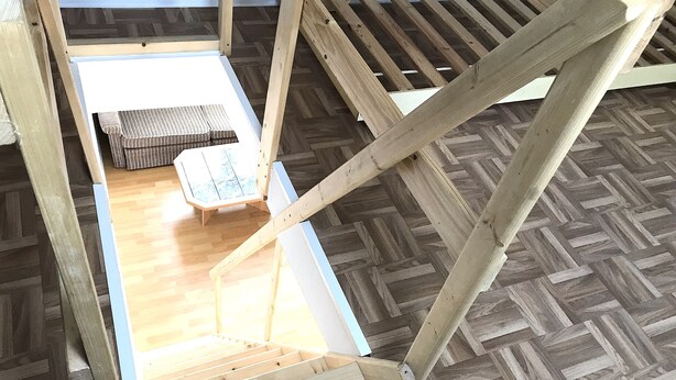A room with a wooden floor, a small table, and a bench. - Meeraner Parkresidenz (Meerane)