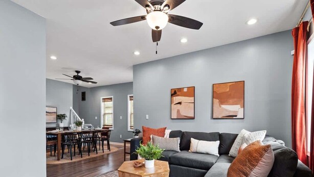 A modern living room with a grey sofa, a coffee table, and a dining area with a table and chairs. - Hot Tub - N64 - Mins to Downtown - Sleeps 8 (Cleveland)
