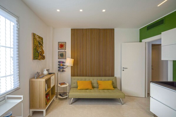 A modern living room with a sofa, a wooden sideboard, a lamp, and artwork on the wall.