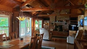 Ein gemütliches Blockhaus-Interieur mit Essbereich, Kamin und Fernseher.