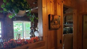 Ein Interieur einer Holzhütte mit Essbereich, Kamin und Blick ins Freie.