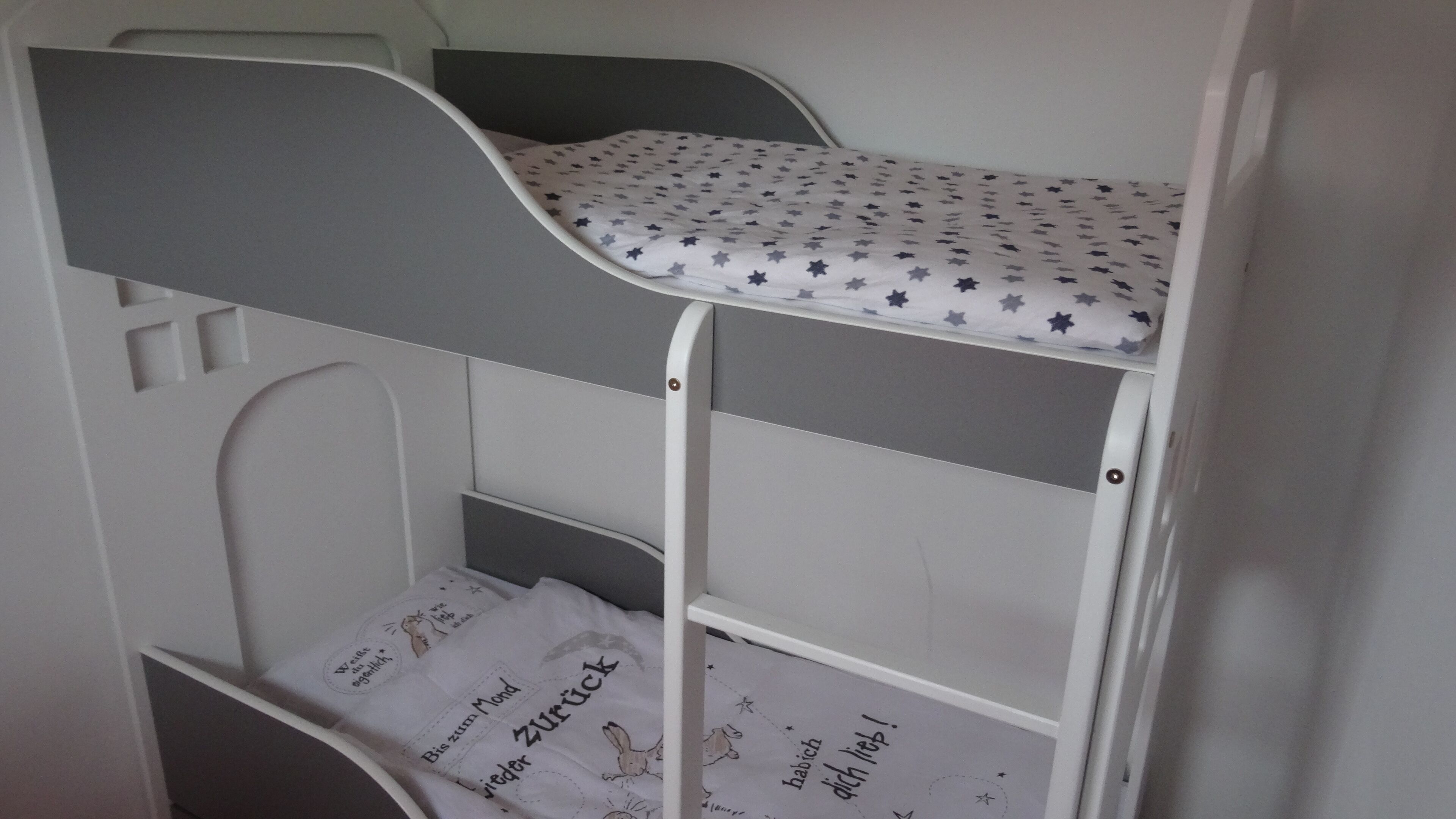 A bunk bed with a star-patterned mattress and a lower bunk with a printed sheet.