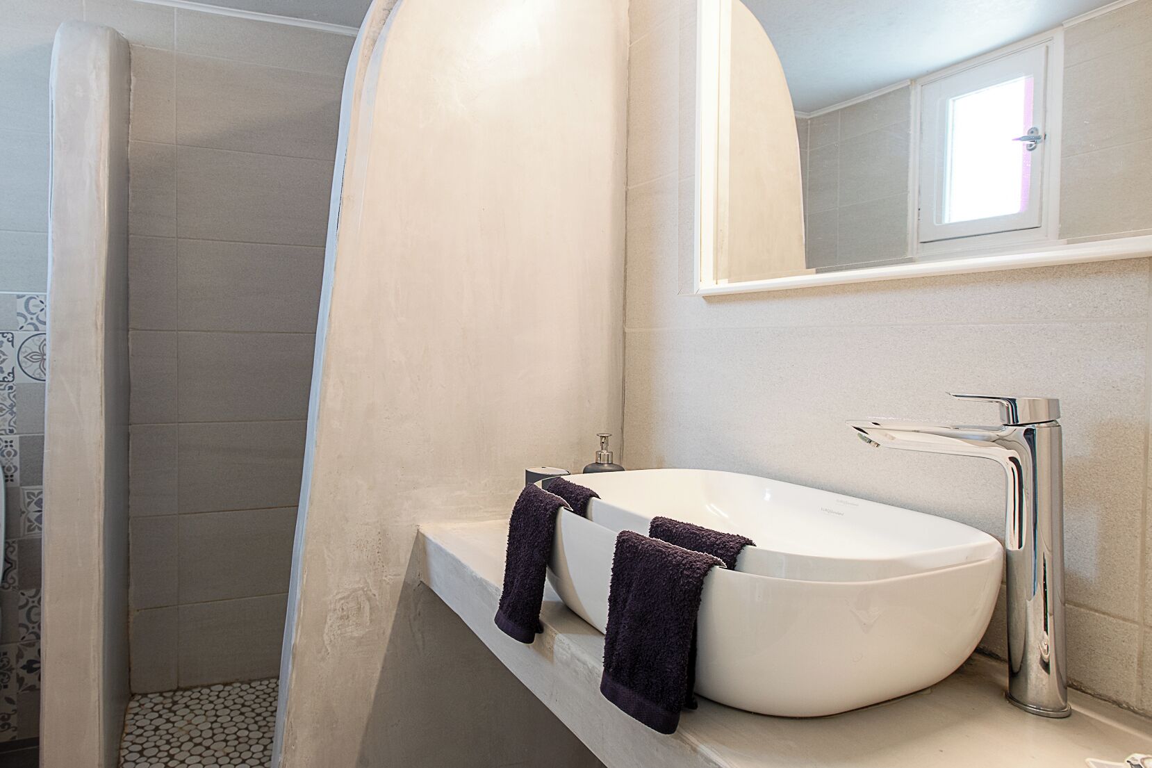 A bathroom with a white sink, a mirror, and a shower area.