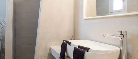 A bathroom with a white sink, a mirror, and a shower area.