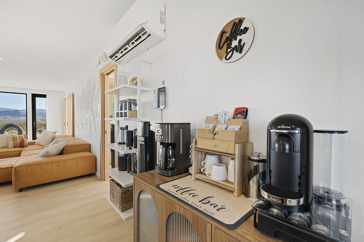 Een moderne woonkamer met een bank, koffiehoek en een bord aan de muur met de tekst 