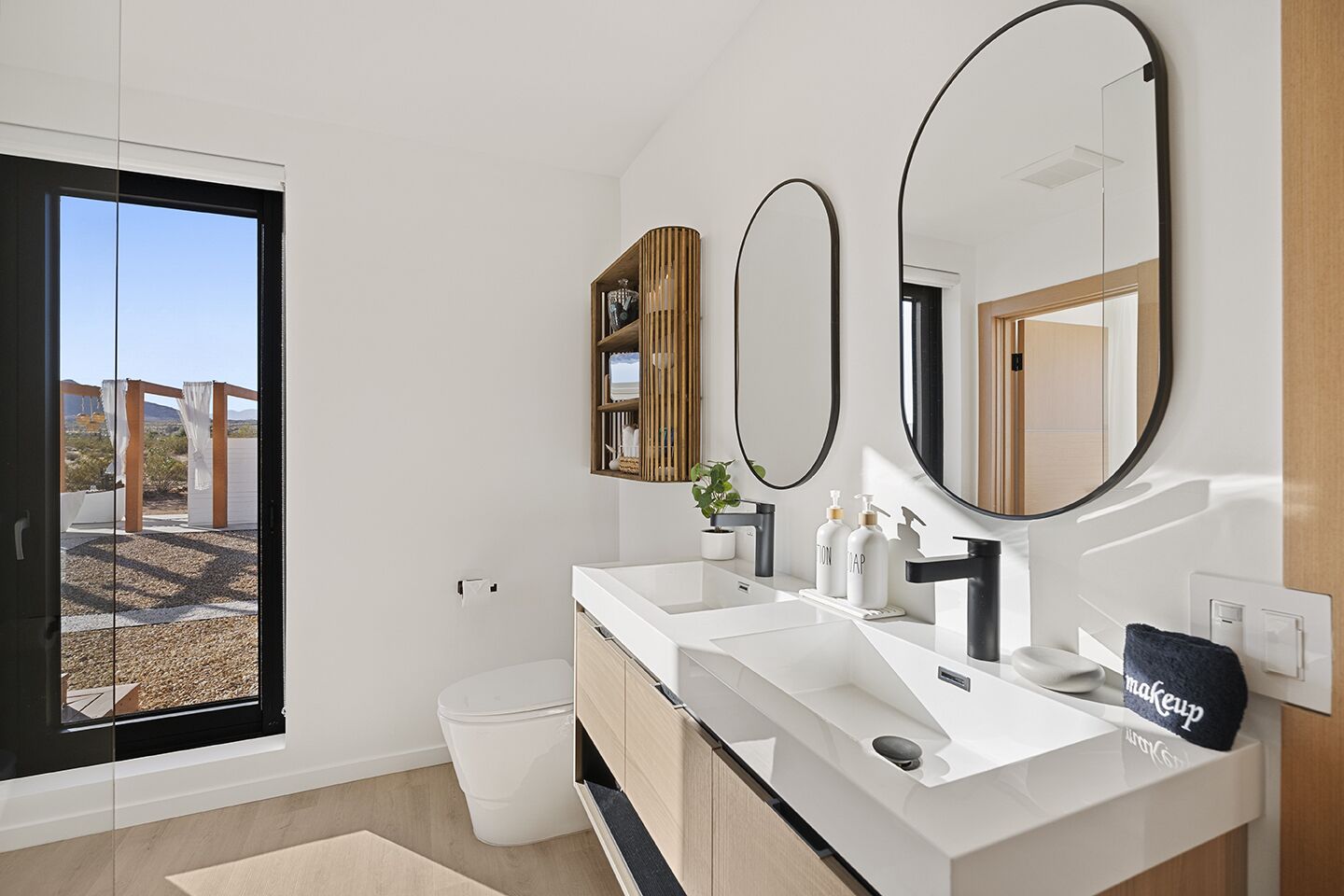 Ein modernes Badezimmer mit einem großen Fenster, zwei Waschbecken, einem Spiegel und einem Handtuchhalter.