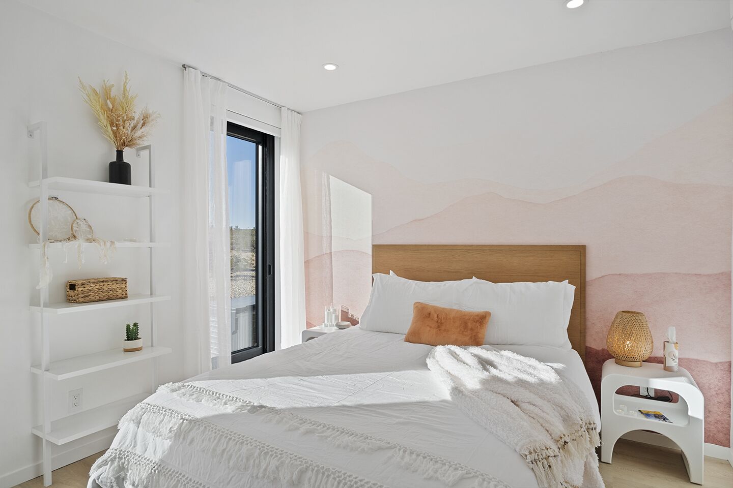 Une chambre moderne avec un grand lit, une étagère blanche et une vue par la fenêtre.