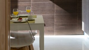 Een moderne eethoek met een witte tafel, twee stoelen en een ontbijtje bestaande uit een bord, twee glazen sinaasappelsap en een aardbei.