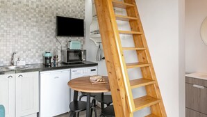 Eine Küche mit einer Holztreppe, einem Esstisch und einer Mikrowelle.
