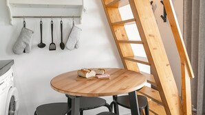Eine Küche mit einem Holztisch, schwarzen Stühlen und einer Holztreppe.