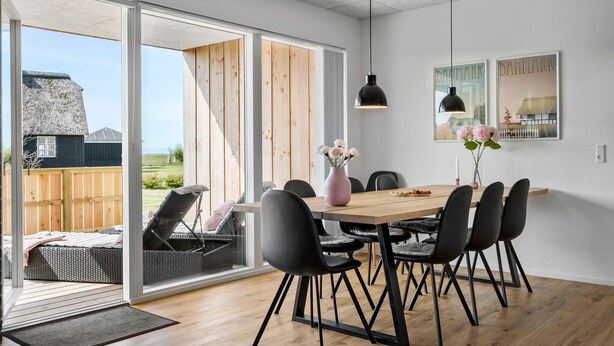 A dining area with a wooden table, black chairs, and a vase of flowers.