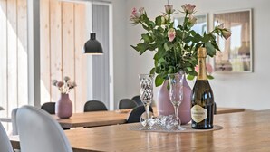 A dining table with a bottle of Scavolino Moscato, two clear wine glasses, and a vase with pink roses.