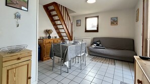 Un coin repas avec une table dressée pour quatre personnes, un canapé, un escalier et une fenêtre.