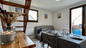 Un coin repas avec une table en bois, des chaises et un vase de fleurs séchées.