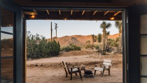 An open garage with a view of a desert landscape, including cacti and a wooden bench area. - Joshua Tree Hidden Tower - View - Landmark - Across from National Park - Pets OK (Yucca Valley)