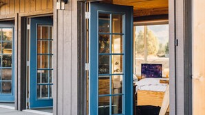 A building entrance with a 'WELCOME' sign, blue doors, and a visible room with a bed and a desk. - Joshua Tree Hidden Tower - View - Landmark - Across from National Park - Pets OK (Yucca Valley)