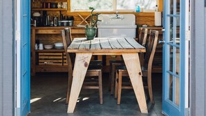A wooden cabin interior with a 'WELCOME' sign, a dining table with chairs, a window, and a sink. - Joshua Tree Hidden Tower - View - Landmark - Across from National Park - Pets OK (Yucca Valley)