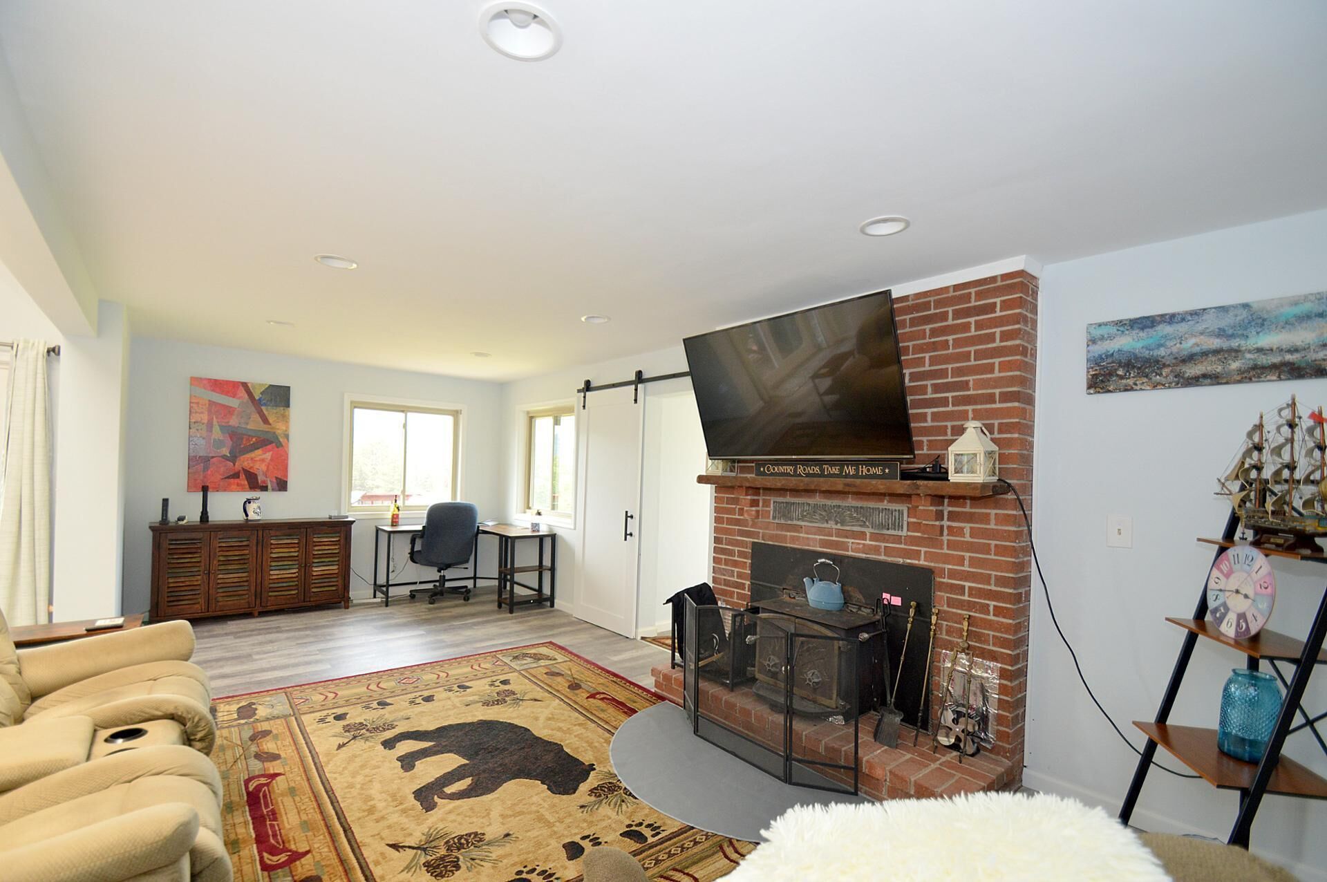 Una sala de estar con chimenea, televisor y un tapete grande.