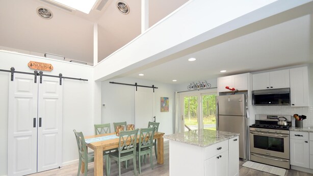 A modern kitchen with white cabinets, a stainless steel refrigerator, and a gas stove. - Black Bear Cabin - The Mountain Retreat! (Berkeley Springs)