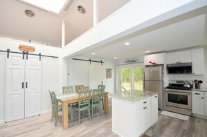 A modern kitchen with white cabinets, a stainless steel refrigerator, and a gas stove. - Black Bear Cabin - The Mountain Retreat! (Berkeley Springs)