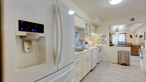 Eine moderne Küche mit integriertem Kühlschrank, Wasserspender und einem Edelstahl-Mülleimer.