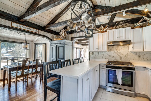 A kitchen with white cabinets, a large island, and a stainless steel oven.
