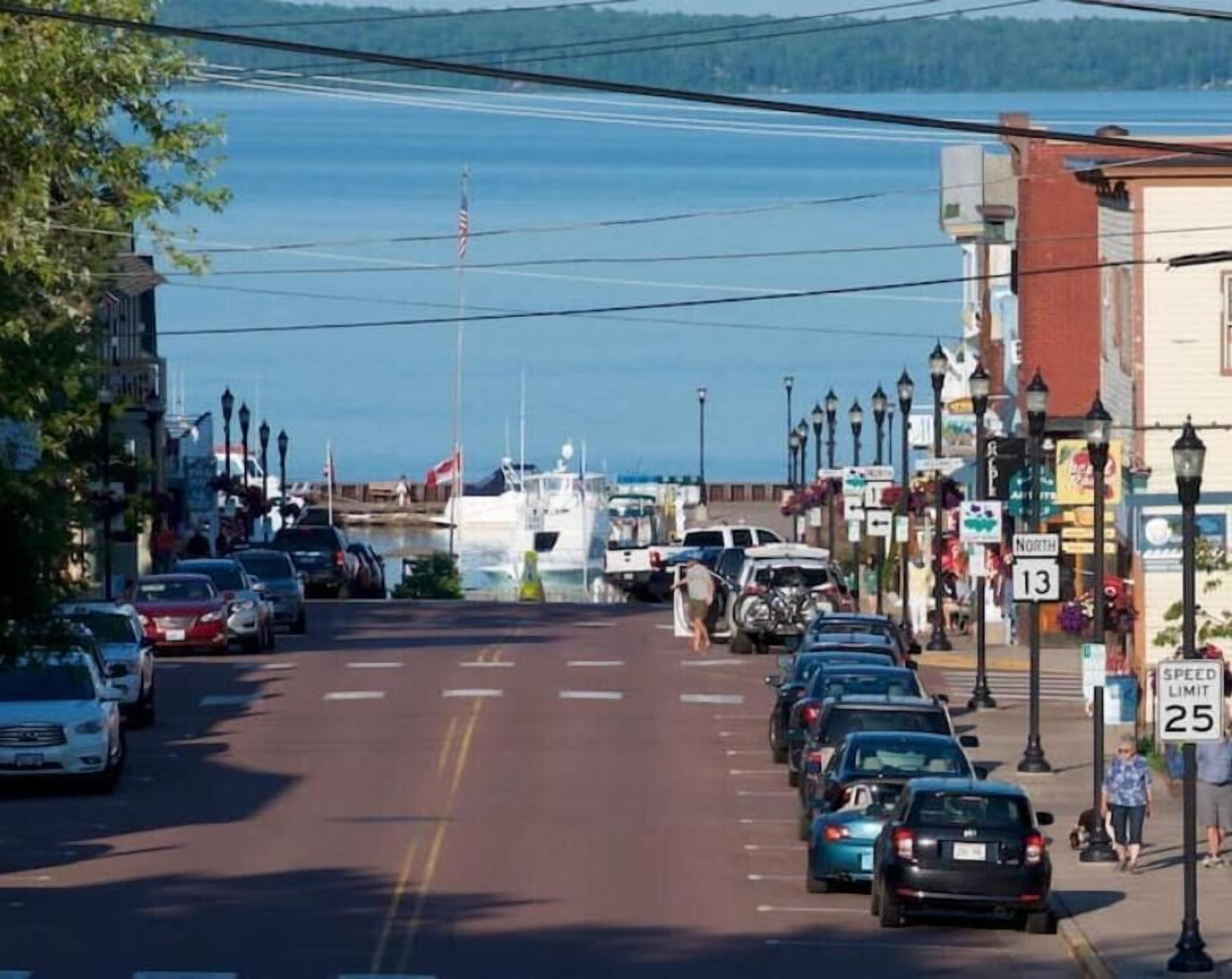 Une rue bordée de voitures garées, un quai pour bateaux et un panneau indiquant une limitation de vitesse à 40 km/h.