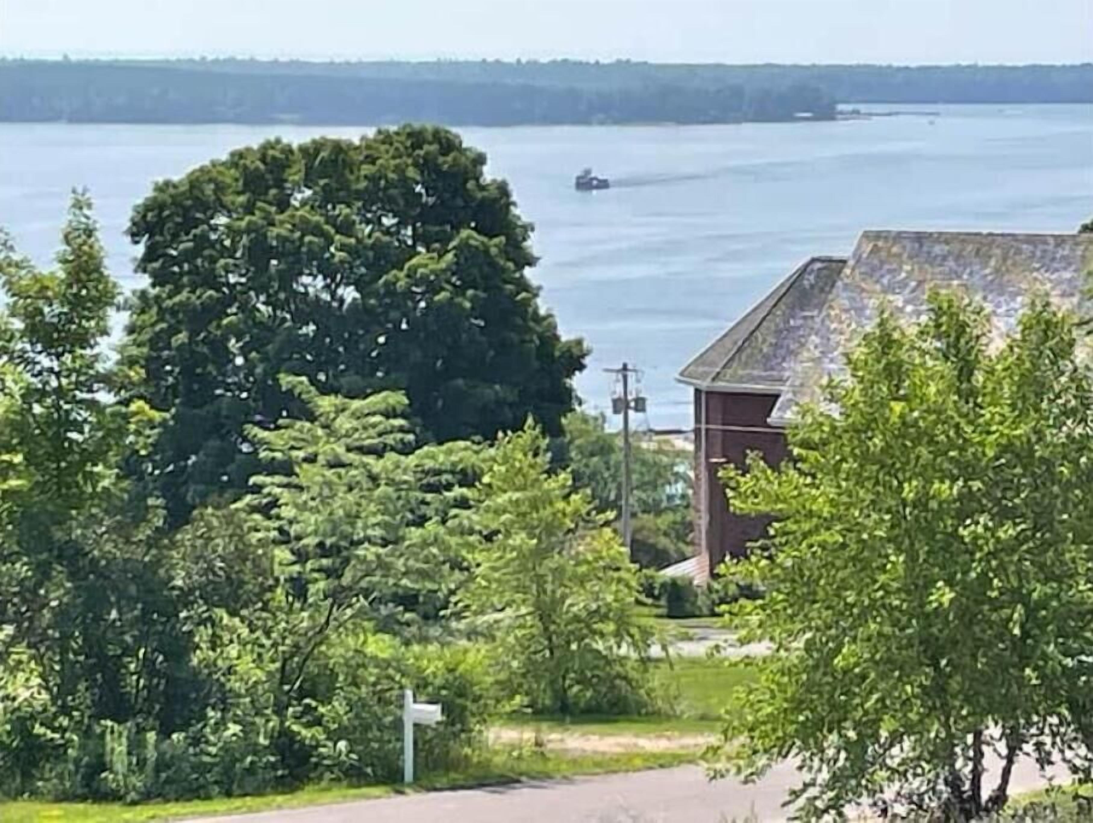 En vy över en sjö med en båt i fjärran, omgiven av frodig grönska och en byggnad med ett sluttande tak.