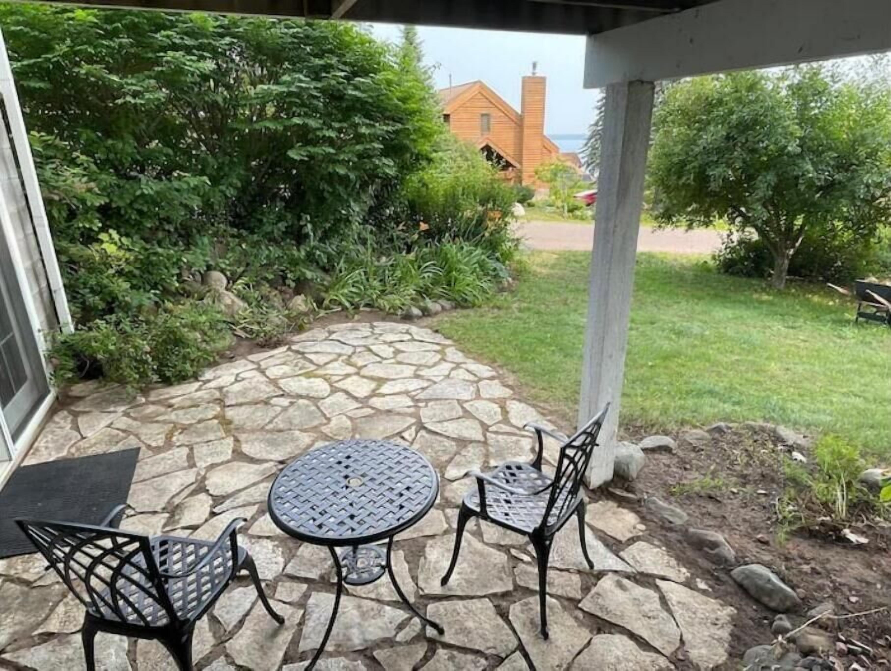 A patio with a stone floor, a round table, and two chairs.