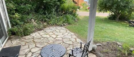 A patio with a stone floor, a round table, and two chairs.