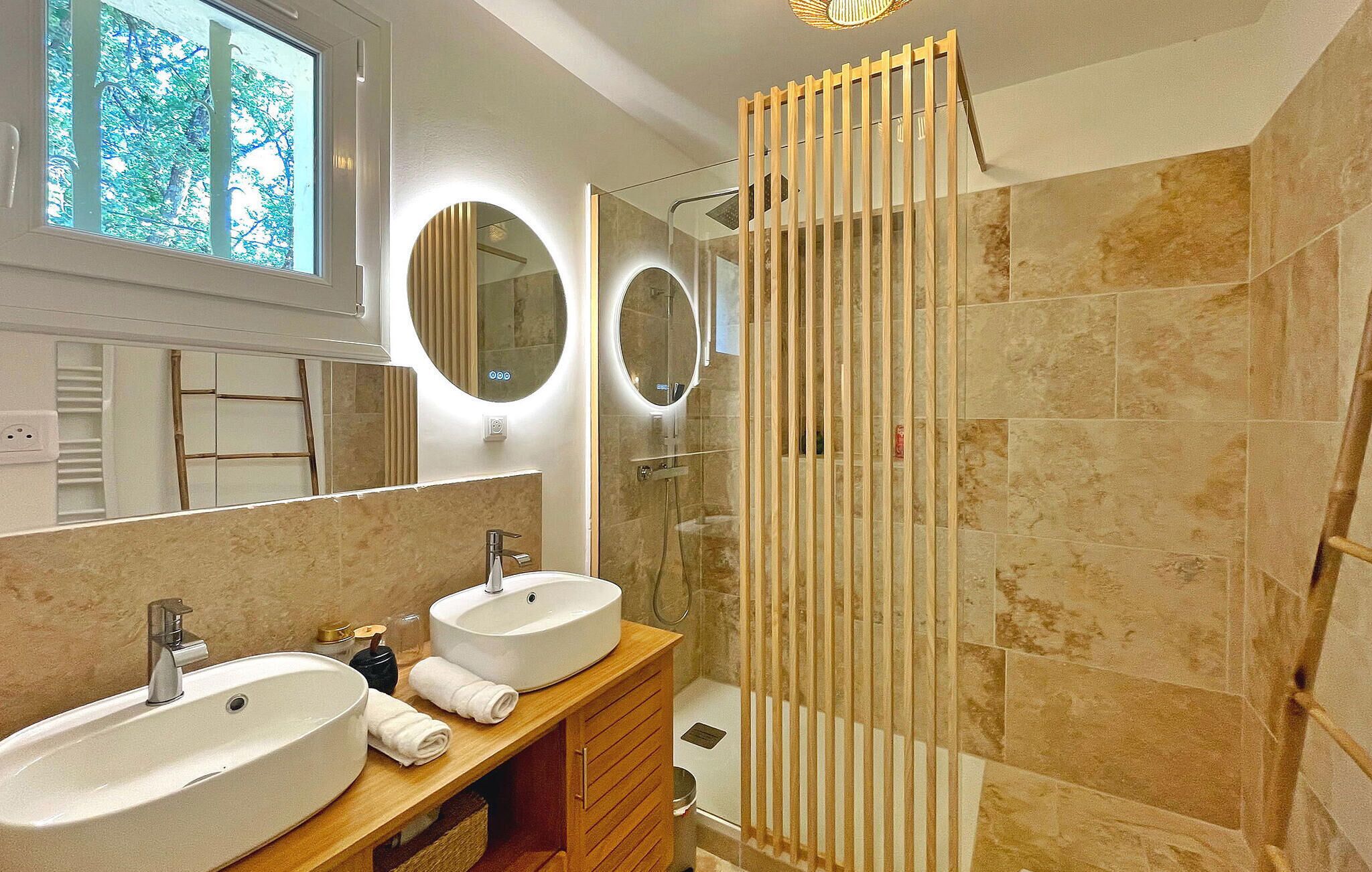 Un bagno moderno con due lavandini, uno specchio e una cabina doccia in vetro.