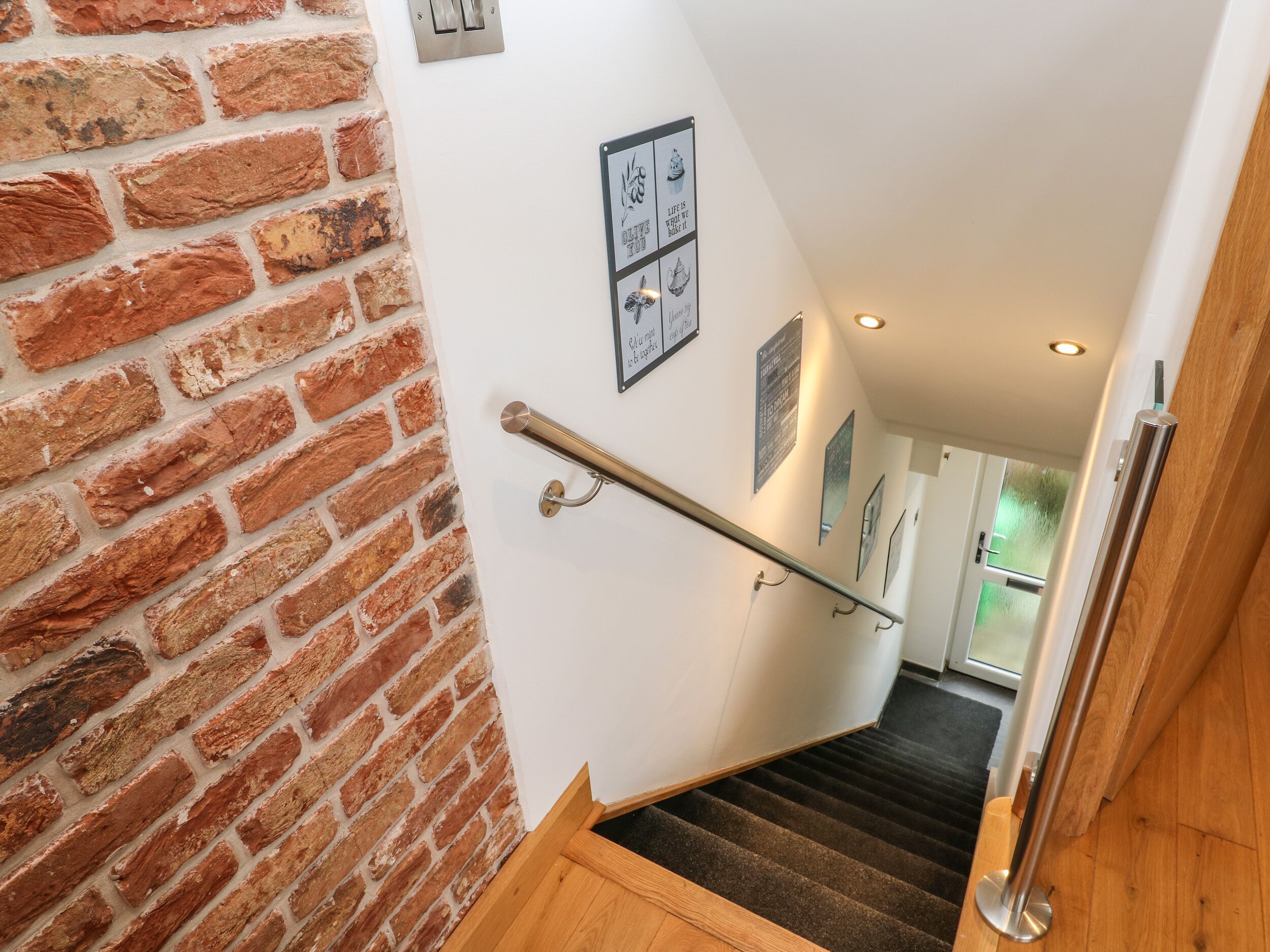 A staircase with a brick wall on one side and a wooden handrail.