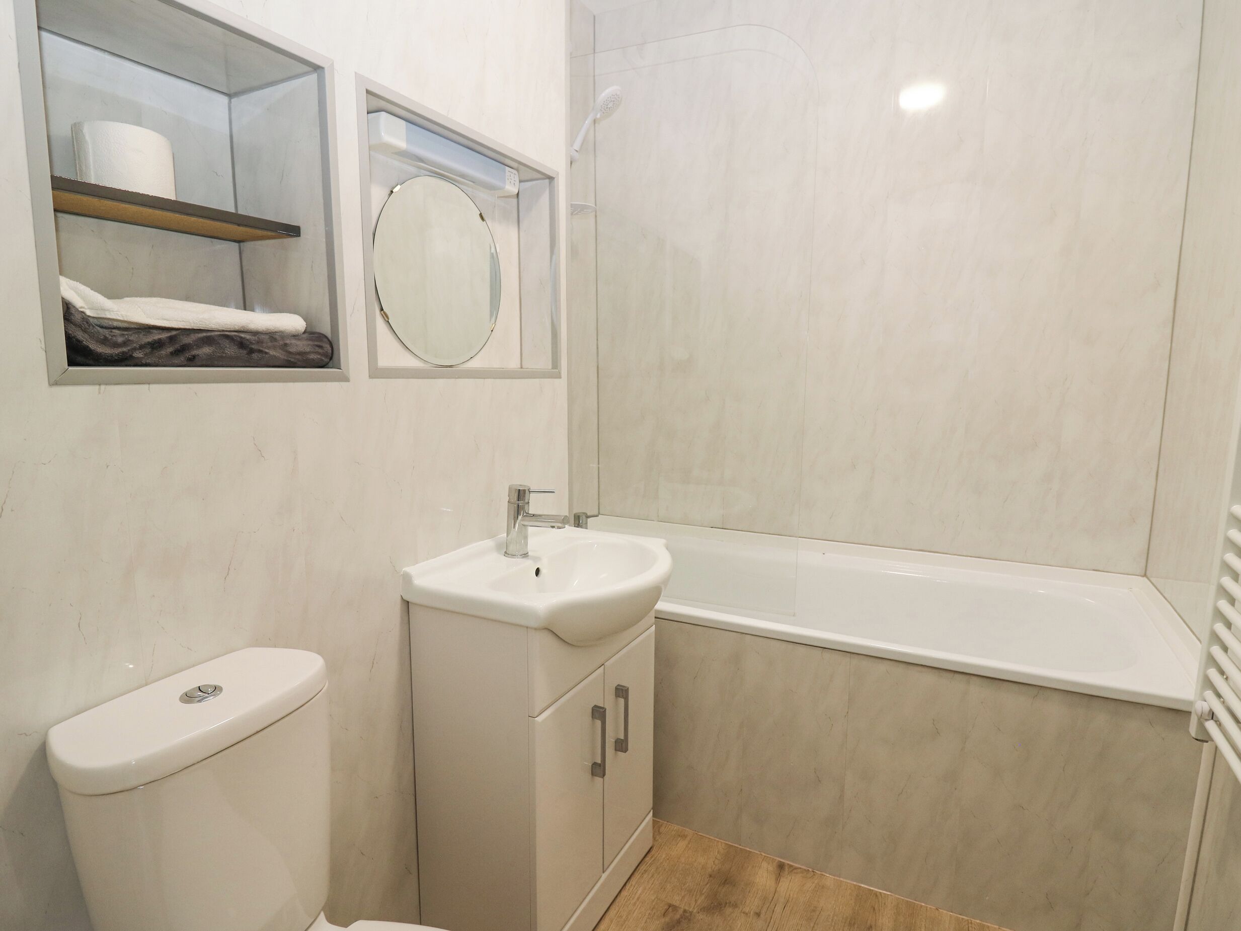 A bathroom with a toilet, a sink, a mirror, and a shower.