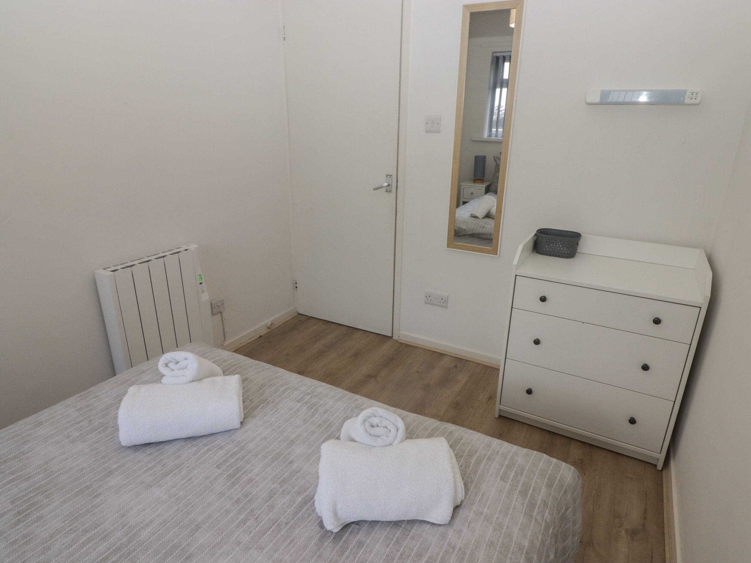 A bedroom with a bed, a dresser, a mirror, and a radiator.