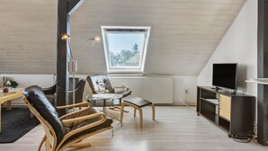 Une chambre de style loft moderne, avec un plafond en pente, une grande fenêtre, un téléviseur à écran plat et un plancher en bois.