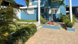 A two-story building with a blue exterior, a tiled entrance, and surrounding greenery including palm trees. - Pousada Encanto dos Mares (Natal)