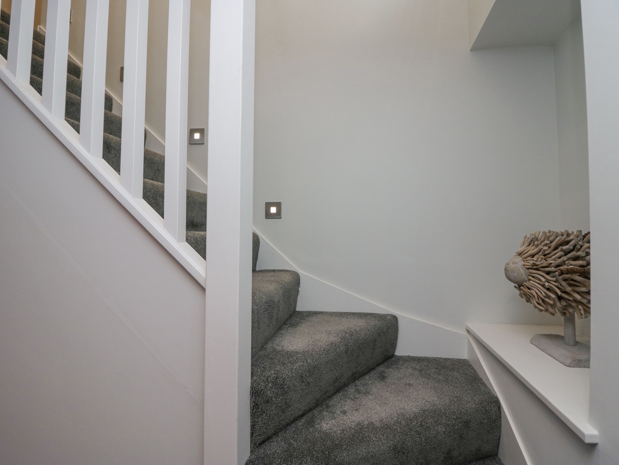 A staircase with a white railing and a wall-mounted light fixture.