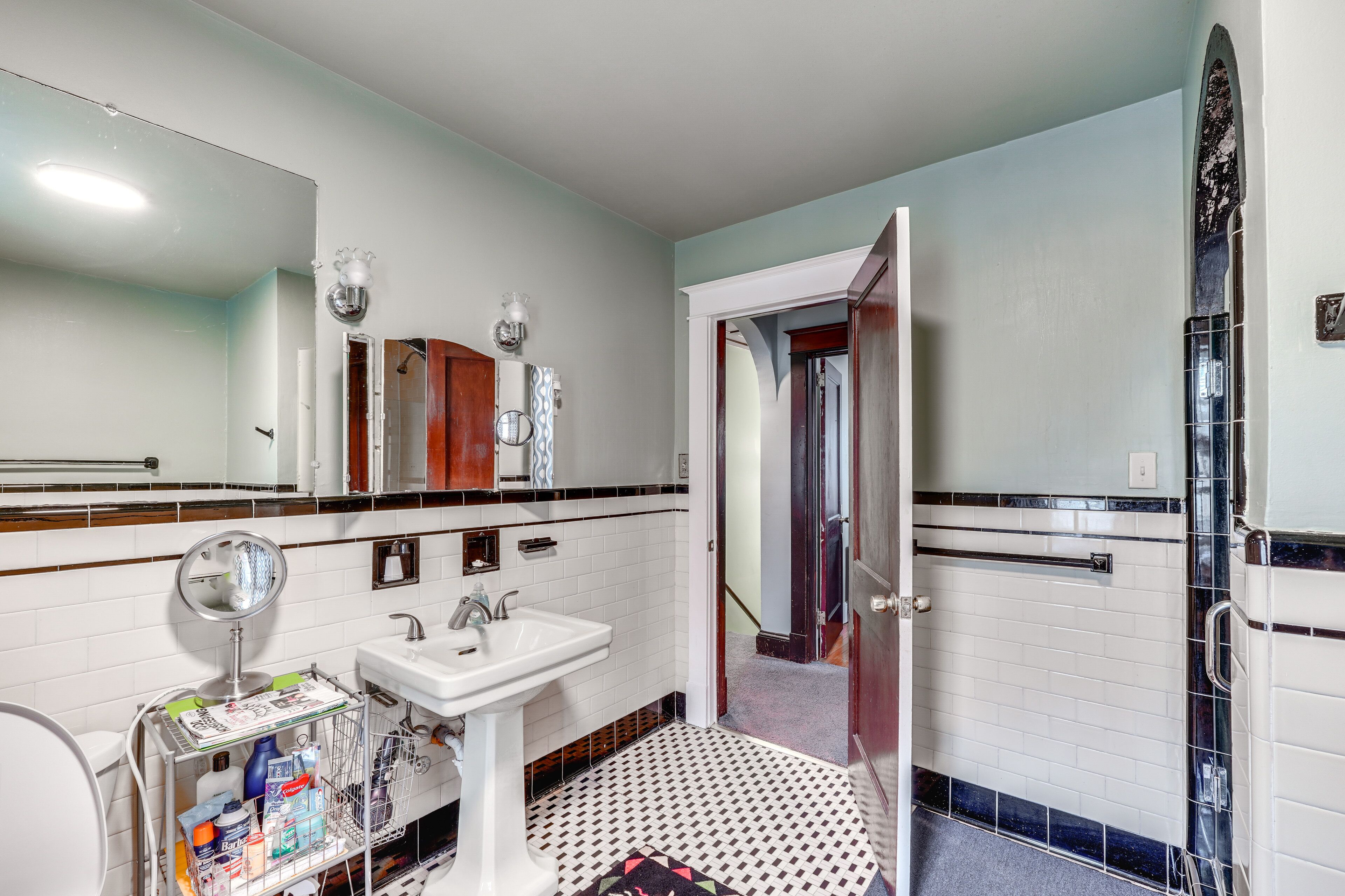 Une salle de bain avec un lavabo blanc, un miroir et un sol carrelé.