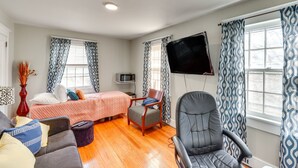 Una habitación con cama, escritorio, silla, televisor y ventana con cortinas.