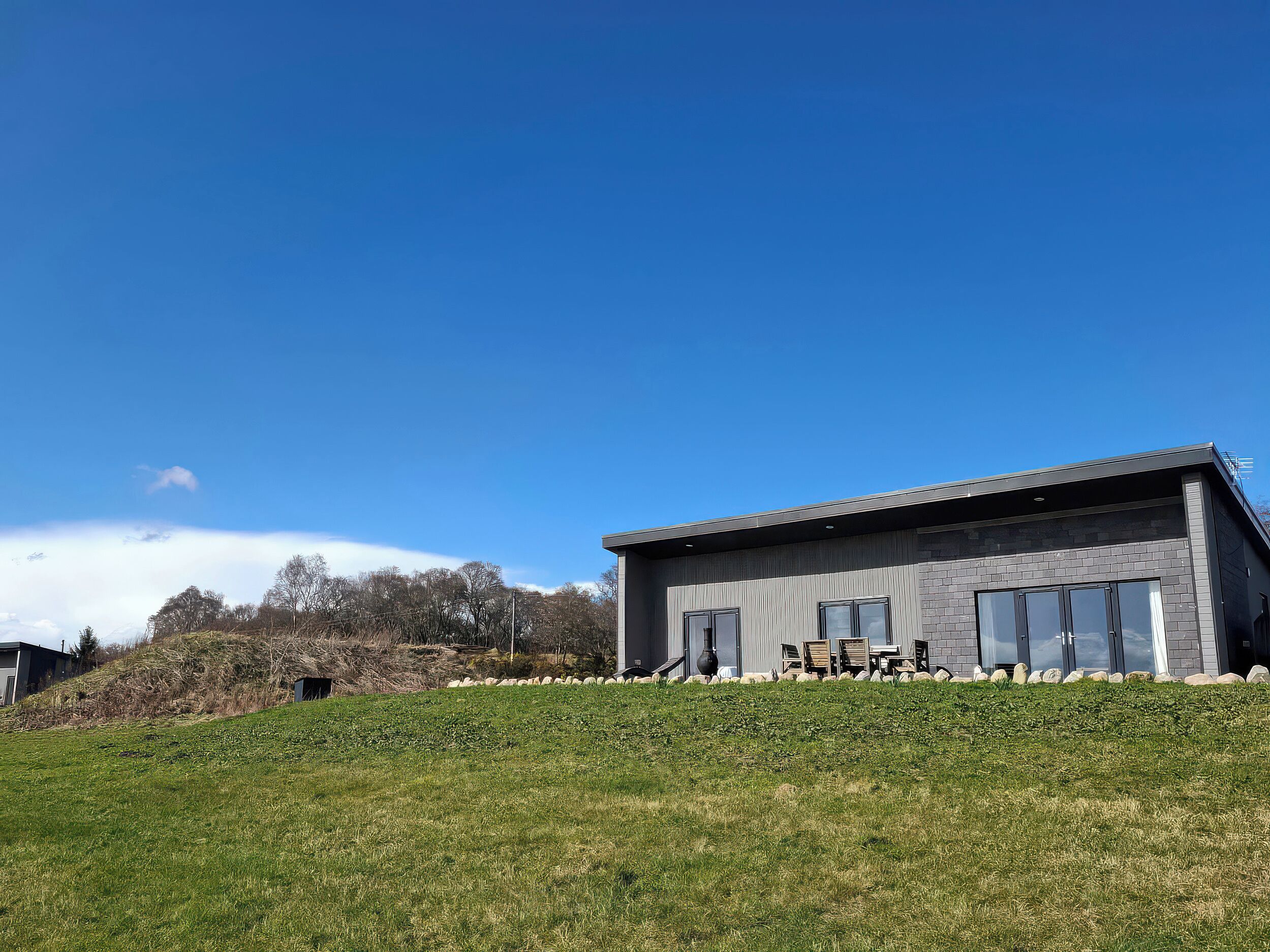 A modern building with a flat roof, large windows, and a stone foundation.