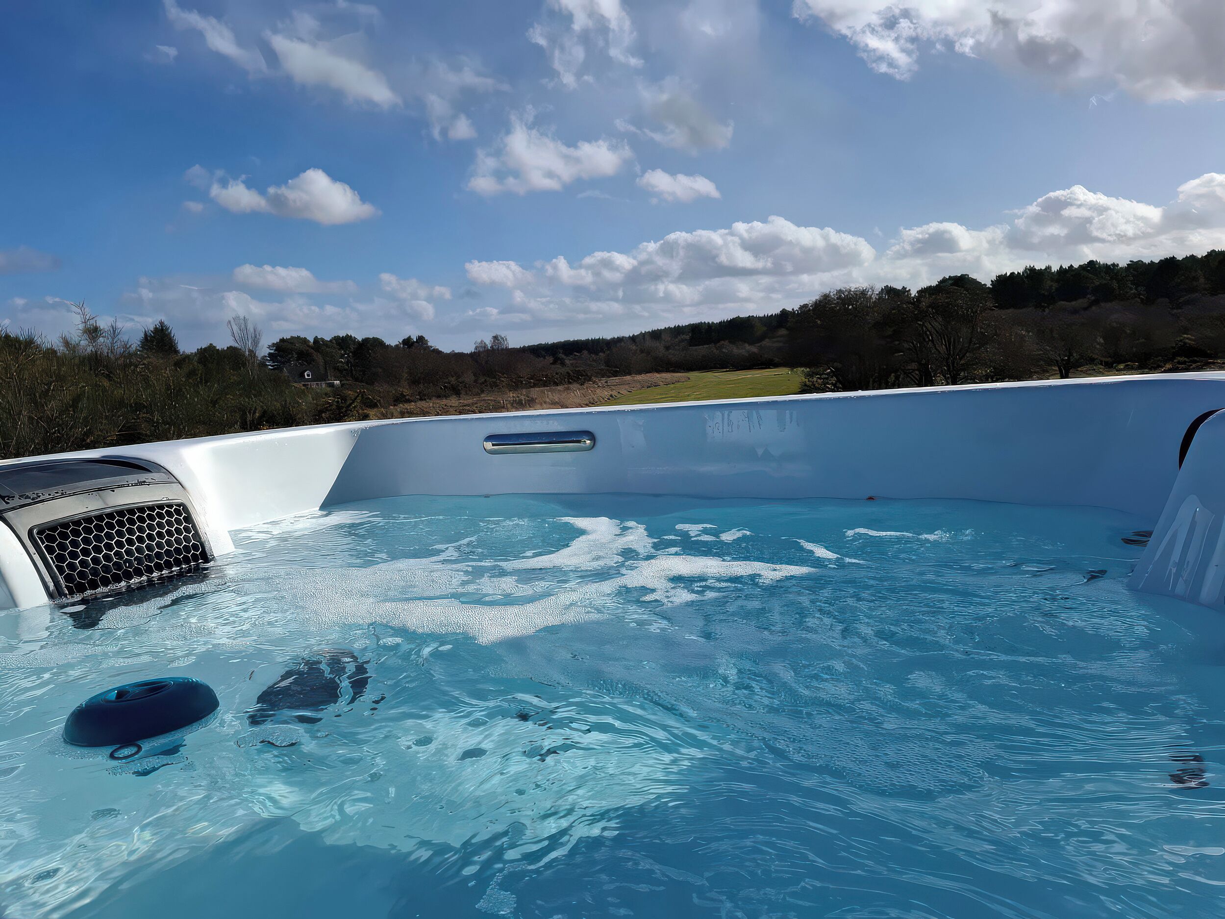 Ein Schwimmbecken mit blauem Himmel und Bäumen in der Ferne.