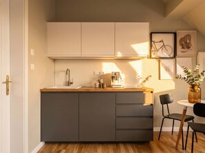 A compact kitchen with a sink, a coffee machine, and a small dining area with a table and chairs.